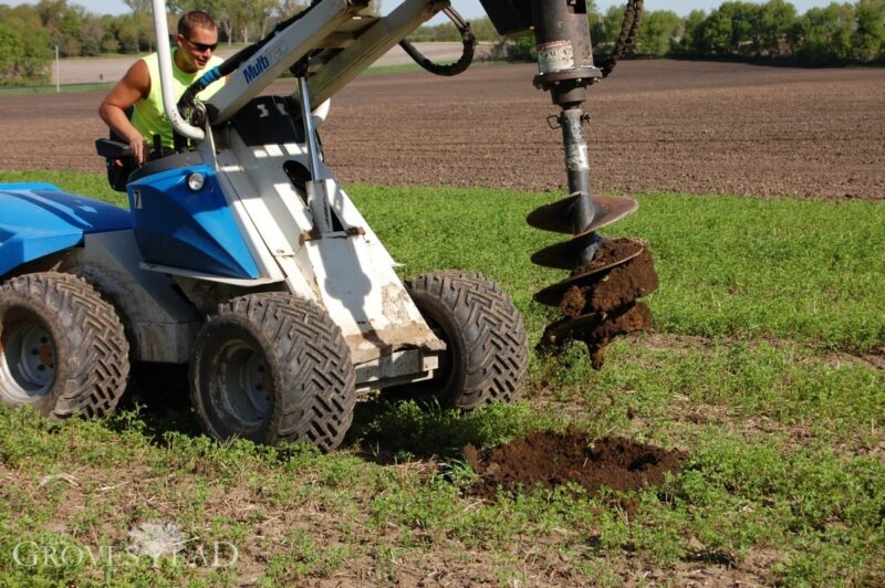 Auger drills holes for apple tree orchard