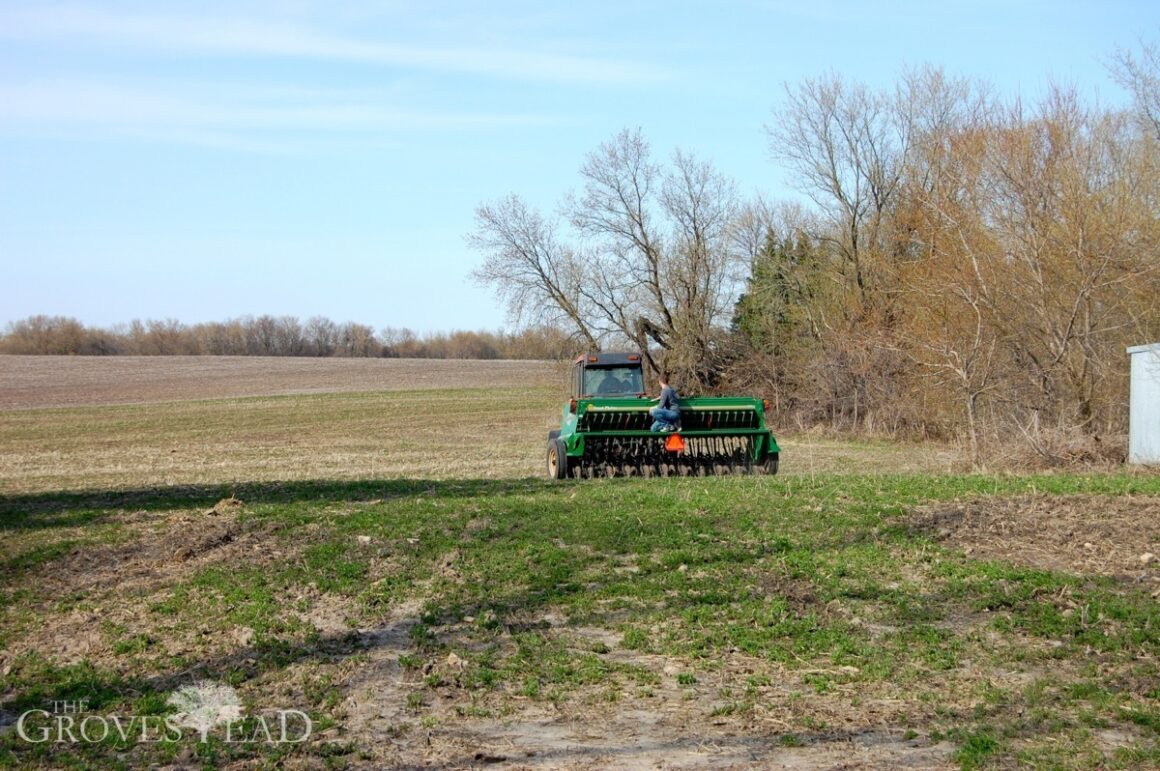 Riding on the seed drill while tractor is planting field