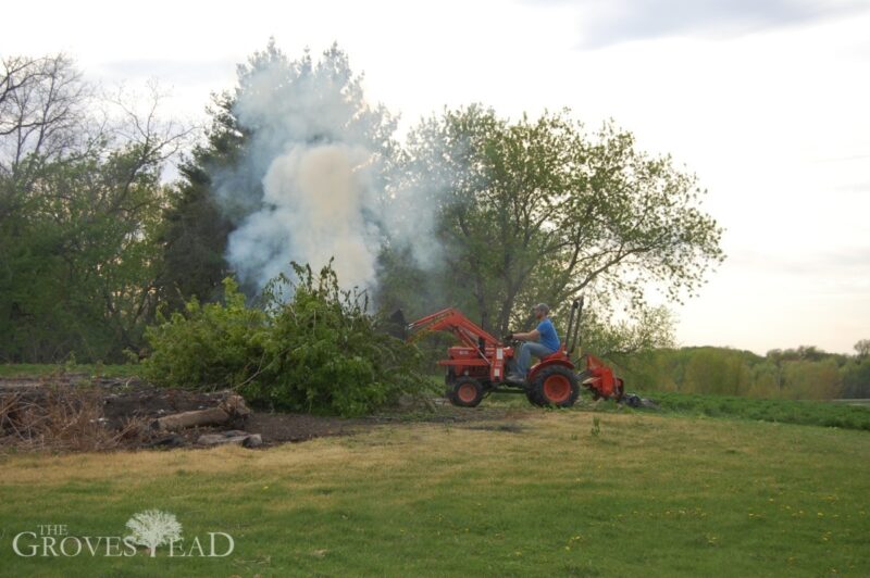 Using the tractor to push trees into the burn pile