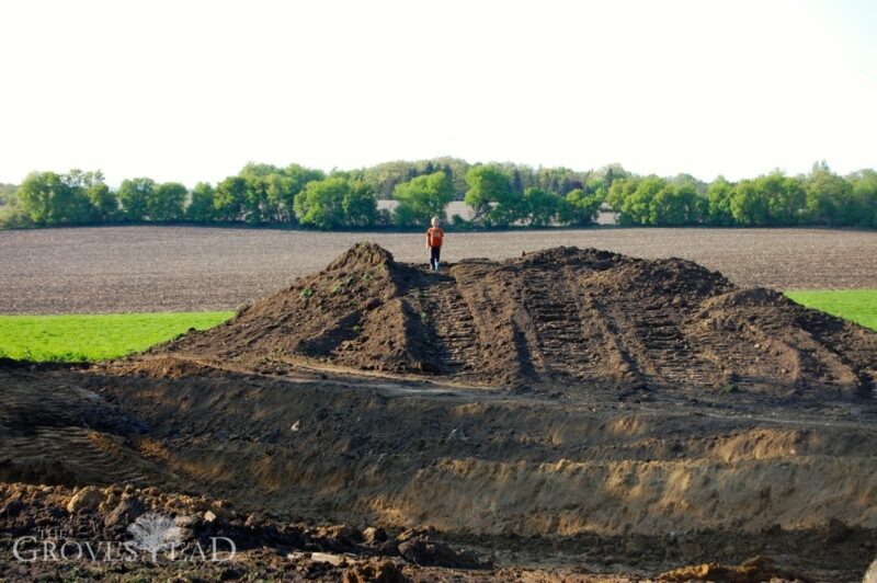 Boy atop excavated hill of topsoil