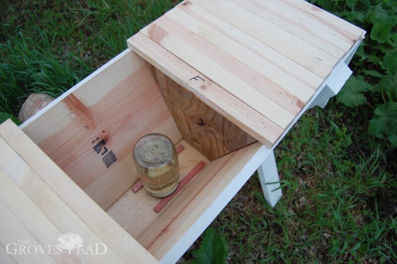 Inside a top bar beehive showing feeder behind follower